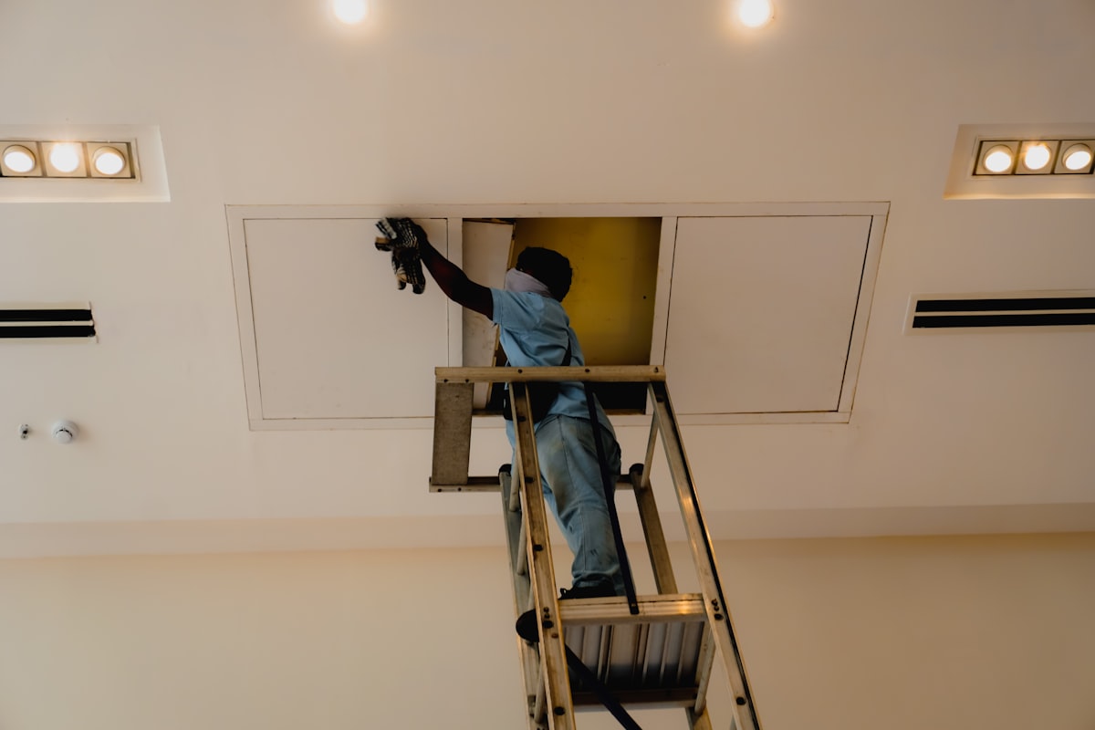 Technician on a ladder installing ducted air conditioning