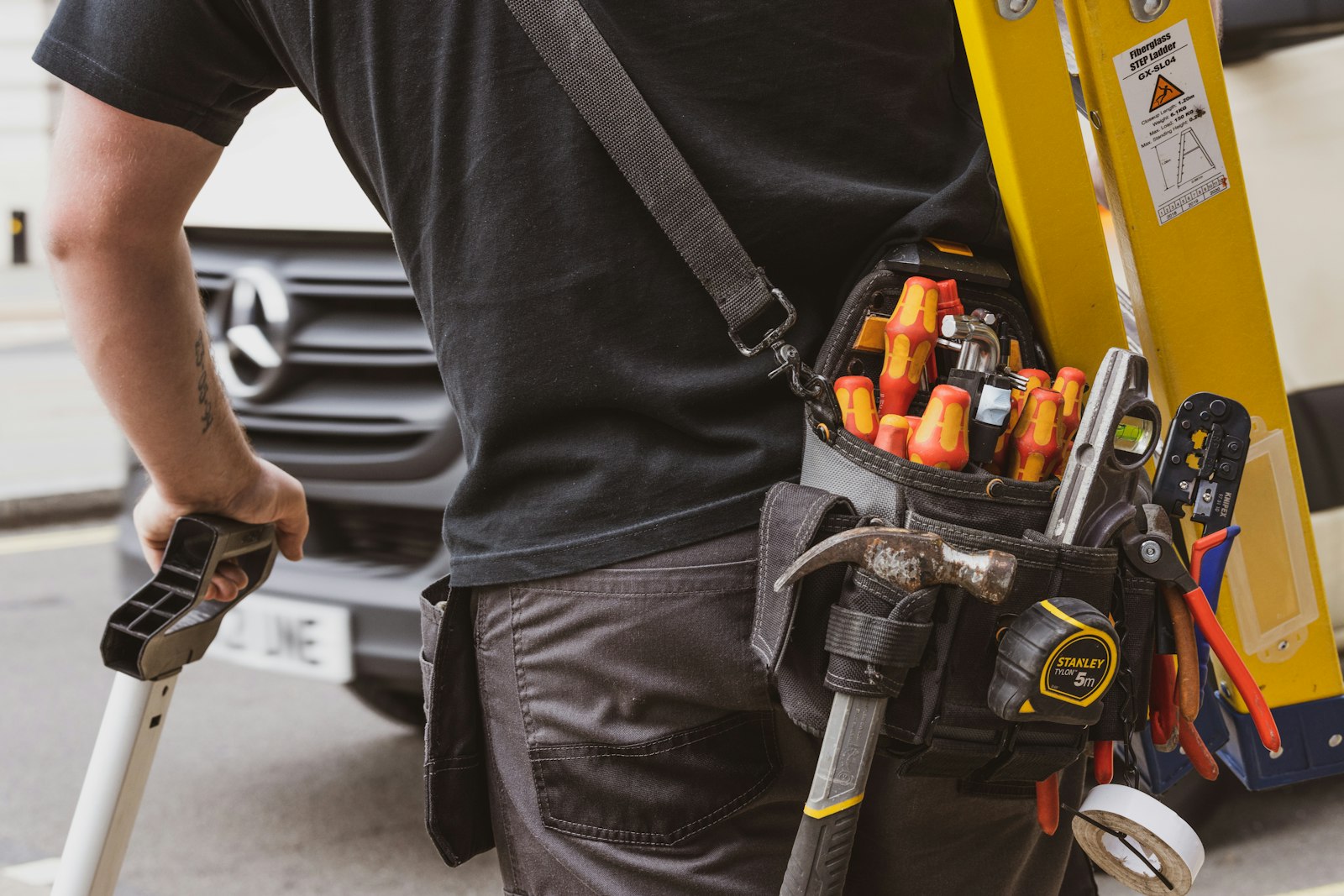 Technician with tool belt on a ladder ready for repairs